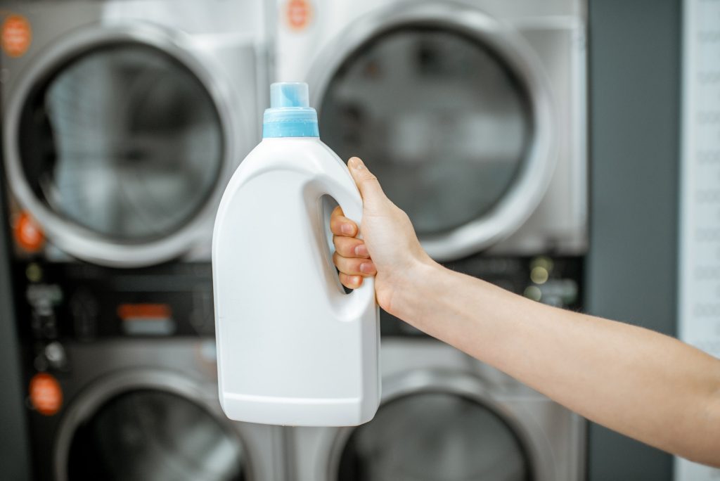 Holding bottle with detergent at the laundry. Como cuidar tus prendas impresas con DTF. Viva DTF venta de transfer DTF por metros