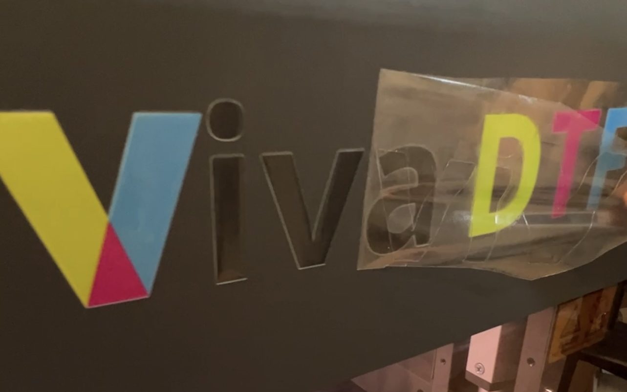 Logo de Viva DTF estampado sobre una máquina industrial. ¿Dónde usar DTF y UV DTF? Viva DTF venta de transfer DTF por metros