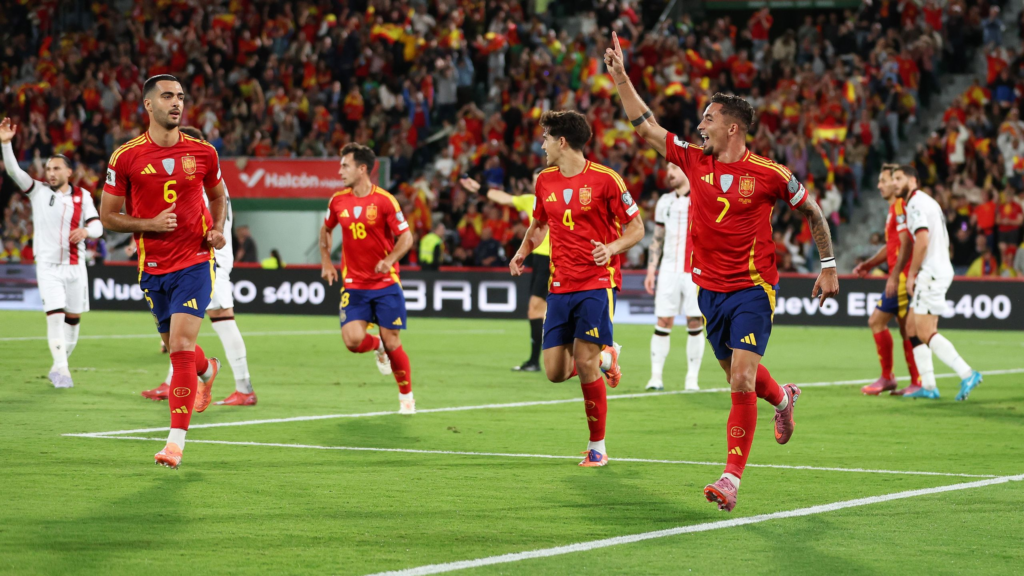 Jugadores de la selección española celebrando un gol en un partido internacional con la afición en el estadio.